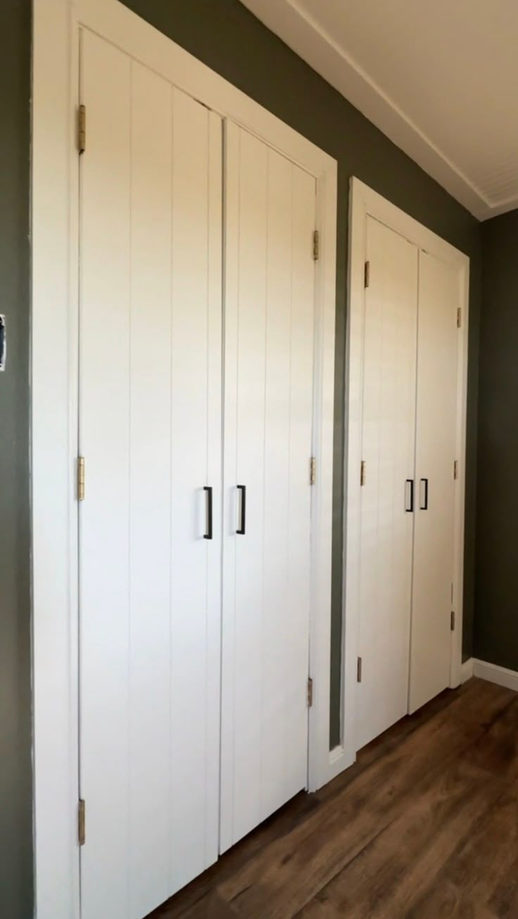 three white closets are lined up against the wall in this empty room with wood flooring