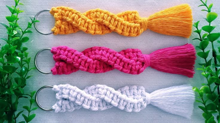 four crocheted tassels in different colors and sizes are shown on a white surface