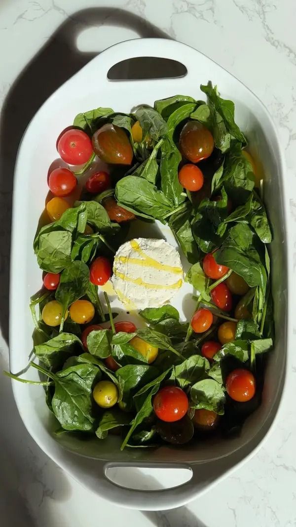 a salad in a white bowl with tomatoes, lettuce and cheese on top