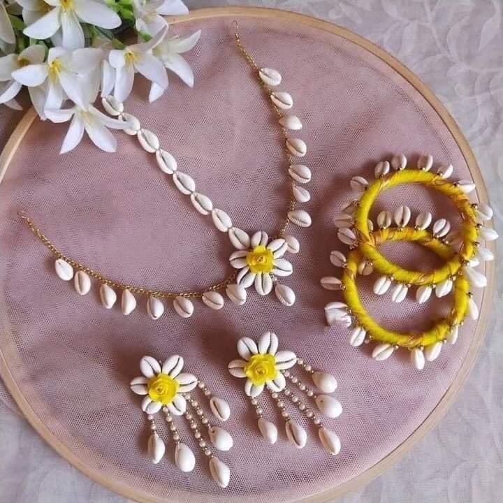 a close up of a embroidery on a table with white flowers and necklaces in it