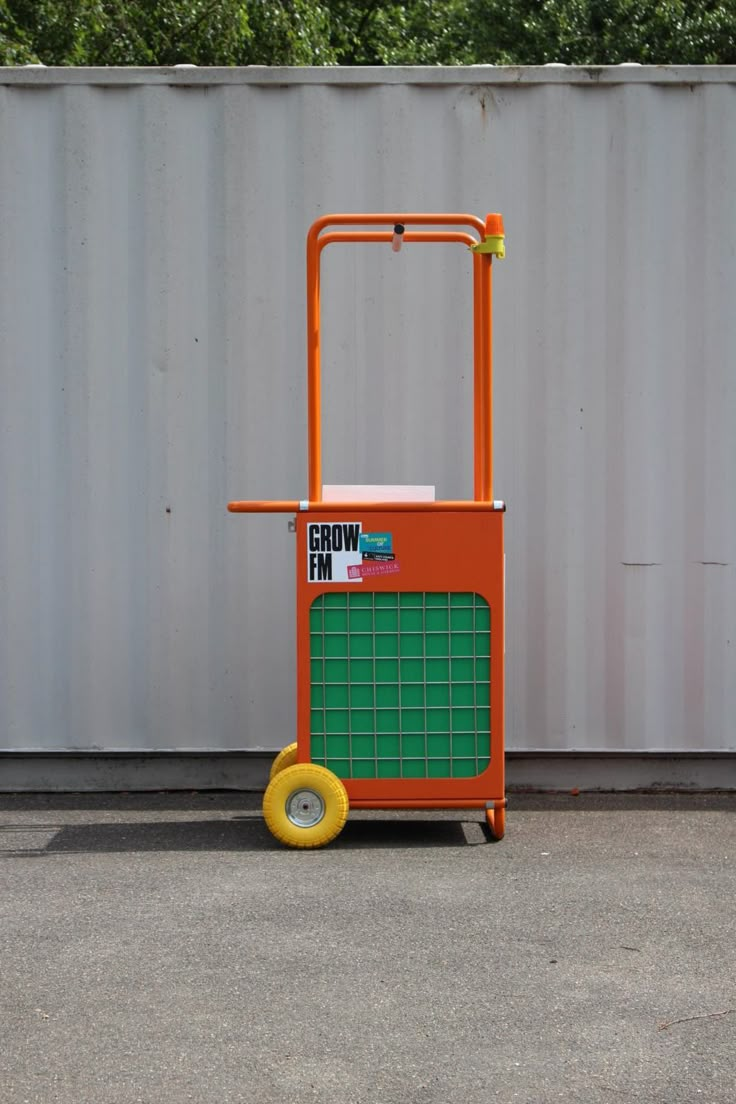 an orange and green cart sitting in front of a wall