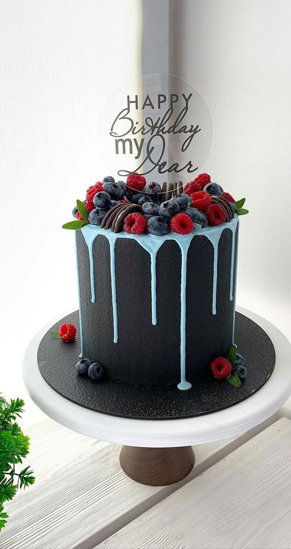 a birthday cake decorated with berries and blue icing