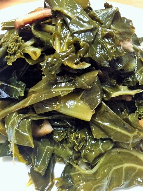 a white plate topped with lots of green leafy vegetables on top of a wooden table