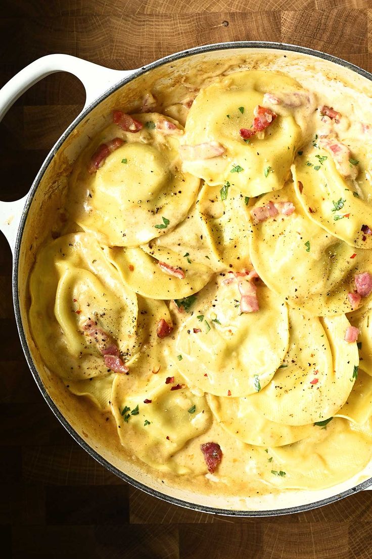 a pot filled with pasta and sauce on top of a wooden table