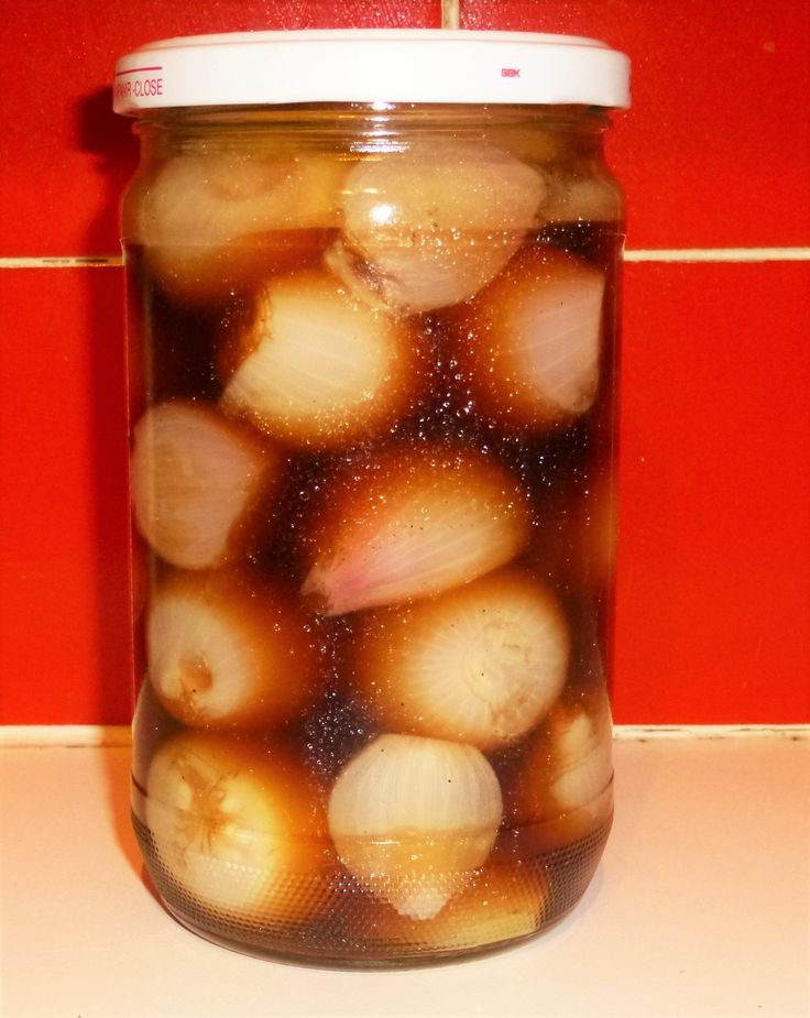 a jar filled with onions sitting on top of a counter next to a red wall