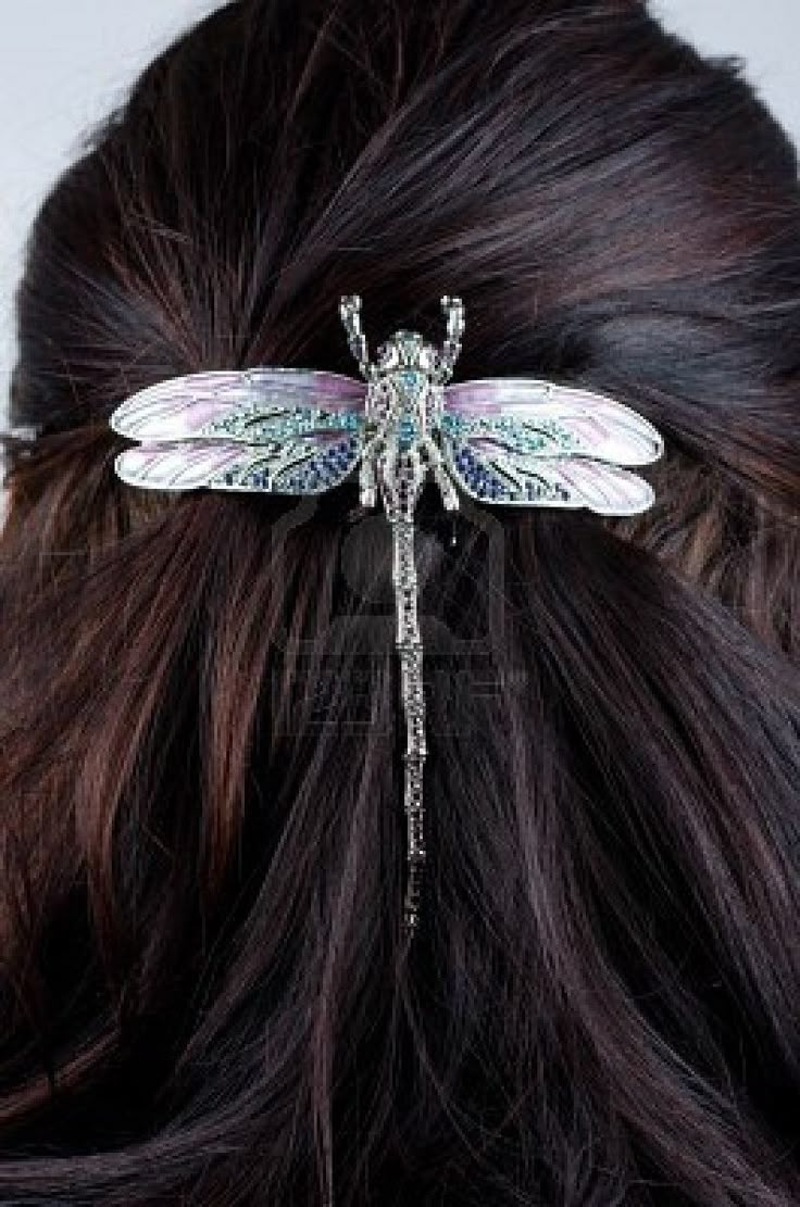 a woman's hair is adorned with a dragonfly brooch