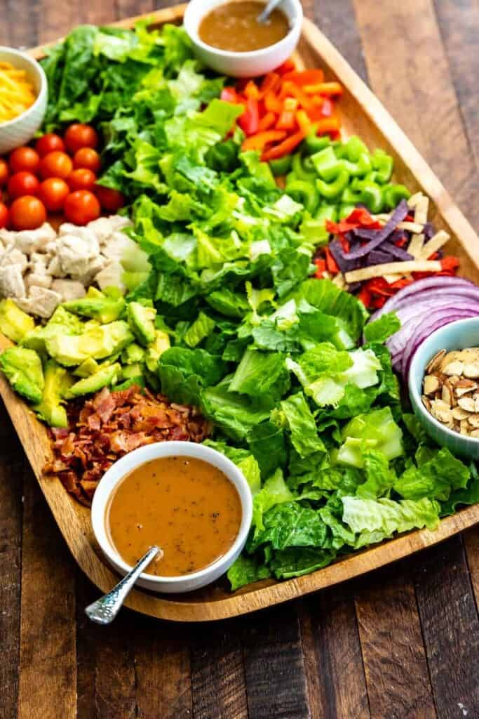 a wooden platter filled with salad and dressing