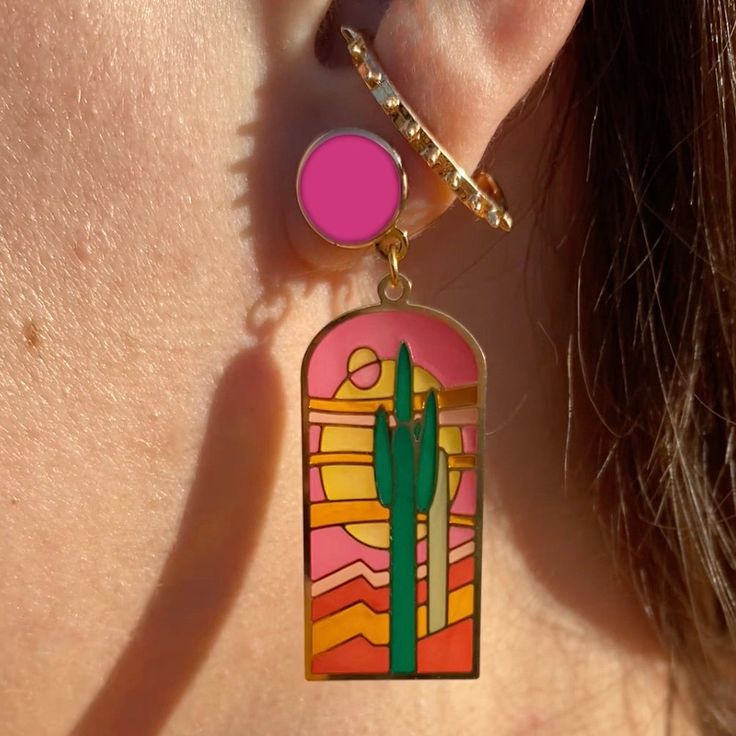 Peek through the TRANSLUCENT windows of these Earrings for a glimpse of desert magic! These "Stained Glass Saguaro" Earrings are made from etched brass & translucent enamel, which looks like stained glass! Let the sunshine in because when the light passes through these they come to life! Drawing inspiration from the intricate artistry of stained glass windows, I've illustrated these artworks to showcase stunning saguaro cacti & desert scenery as if they were a vibrant mosaic. Hand illustrated by Landscape Earrings, Enchanting Landscape, Desert Magic, Order Earrings, Desert Scenery, Stained Glass Earrings, Logo Jewelry, Acrylic Pins, Pink Studs