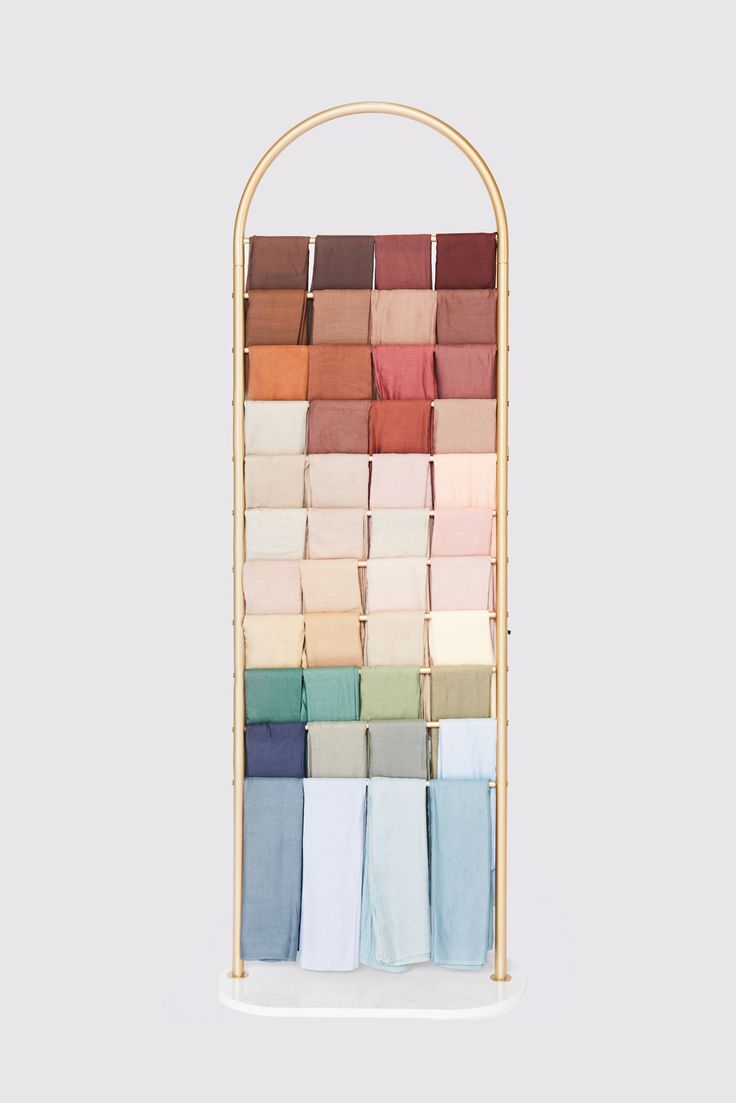 a display rack with several colors of folded fabric on it, and the top shelf is made out of bamboo