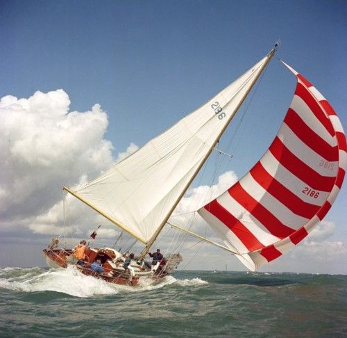 a red and white striped sail boat in the ocean