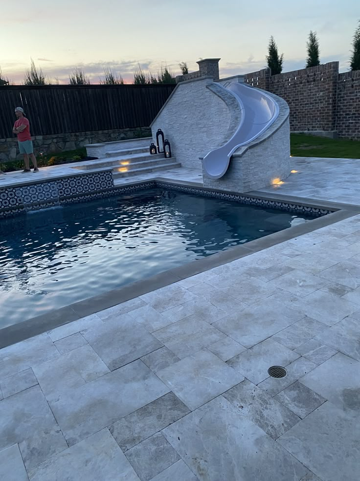 an outdoor swimming pool with steps leading up to it and a slide in the middle