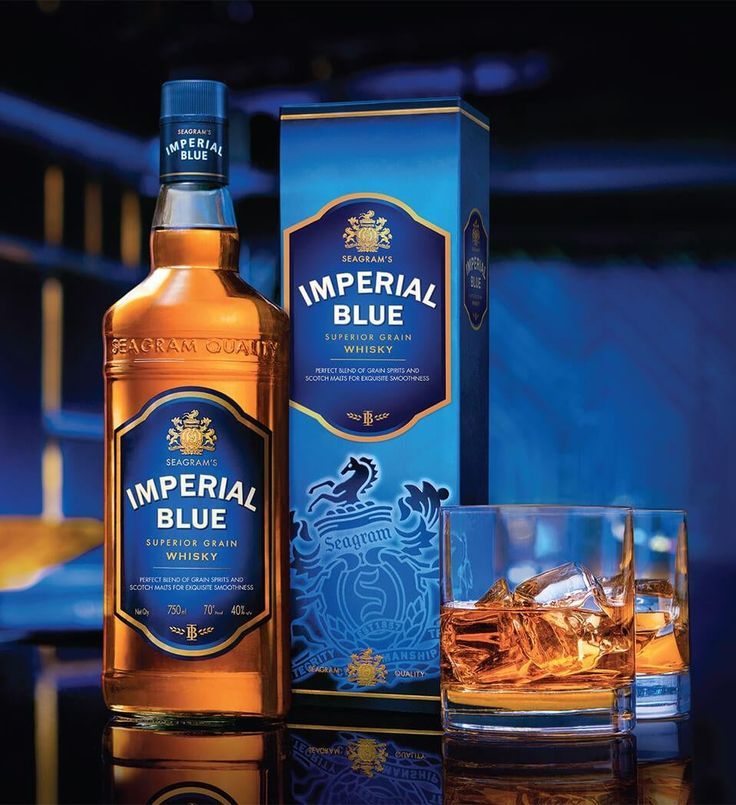 an empty glass next to a bottle of imperial blue