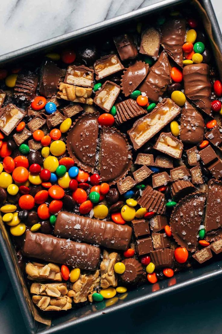 a metal tray filled with lots of different types of candies and chocolates on top of a marble counter