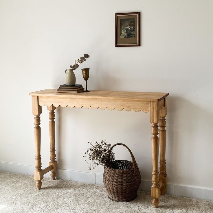 a wooden table sitting next to a basket on top of a white carpeted floor