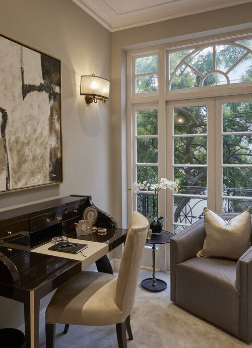 a living room filled with furniture and a painting on the wall next to a window