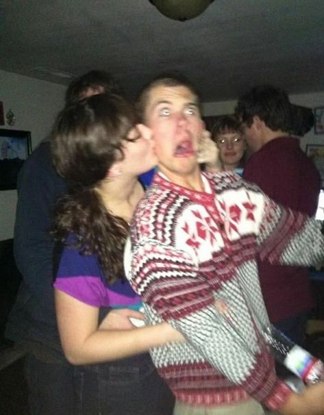 a group of people standing in a room with one person kissing the other's face