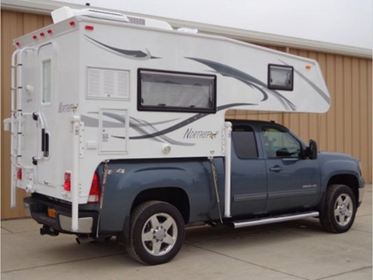 a truck with a camper attached to it's bed parked in front of a building