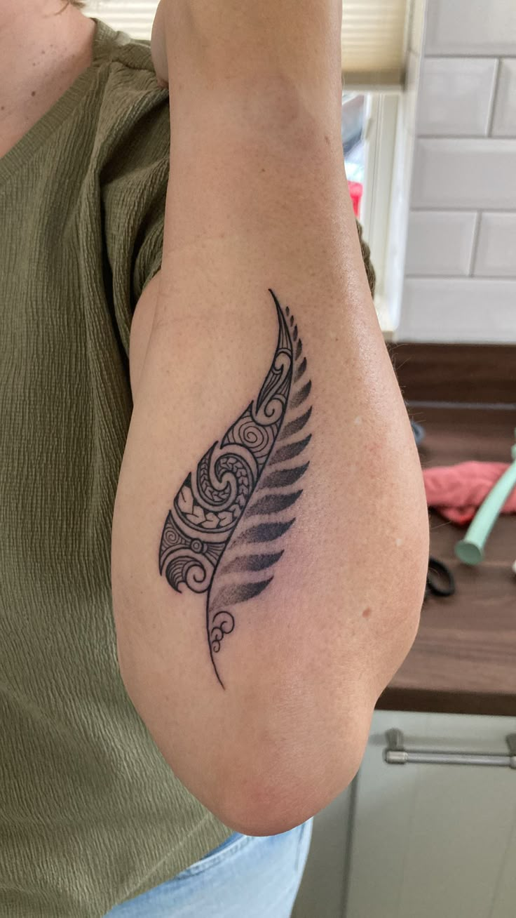 a woman's arm with a tattoo on it and a feather in the middle