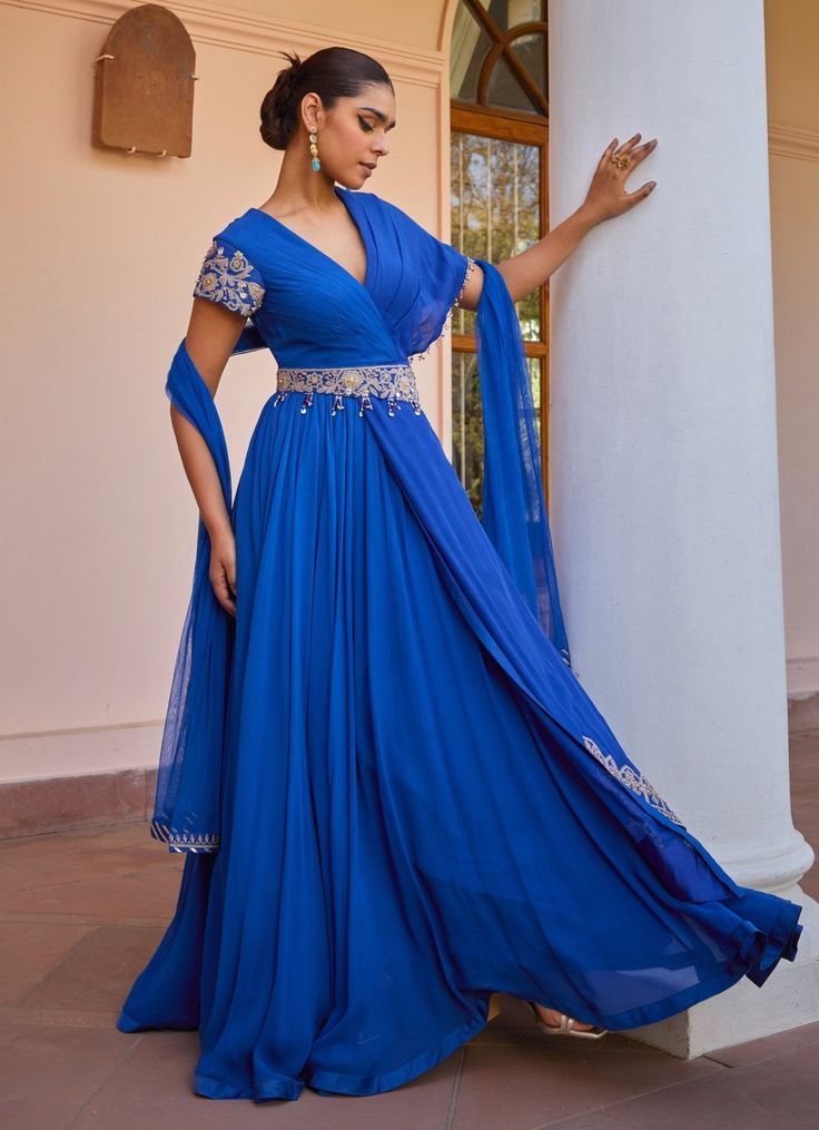 Introducing the timeless Blue Layered Anarkali Gown with Dupatta, crafted from georgette organza. The captivating blue gown features a vibrant hue that exudes elegance and sophistication. Adorned with intricate tilla work, dori, pearls, handmade tassels, brass sequins, and beads, it offers a touch of luxurious detail. The detachable embroidered belt accentuates the waist, creating a flattering silhouette. The soft net dupatta complements the gown, adding an ethereal layer to the outfit. With a s Blue Floor-length Gown For Eid, Evening Georgette Dresses With Cutdana Detail, Evening Georgette Dresses With Cutdana, Evening Gown With Cutdana In Traditional Drape, Evening Anarkali Gown With Cutdana, Blue Dupatta For Evening Eid Festival, Blue Evening Dupatta For Eid, Blue Georgette Anarkali Set With Traditional Drape, Blue Gown With Resham Embroidery In Maxi Length