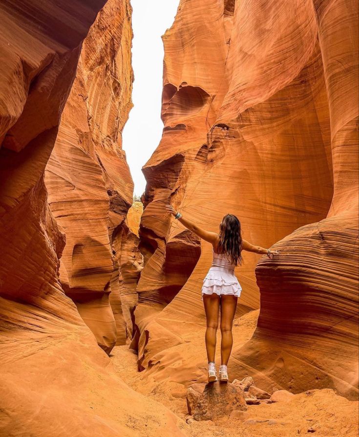 a woman standing in the middle of a canyon