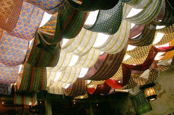 many different colored hats hanging from the ceiling