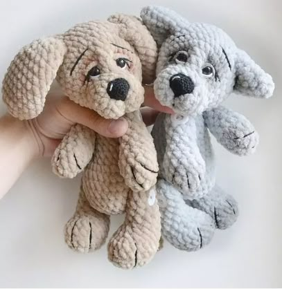 there is a hand holding two stuffed dogs