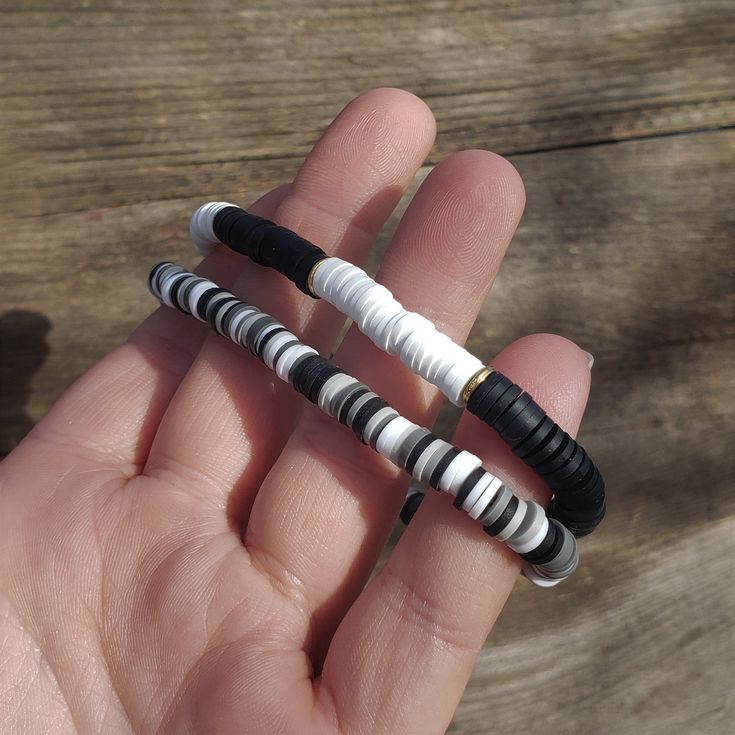 two small black and white beads are held in someone's hand