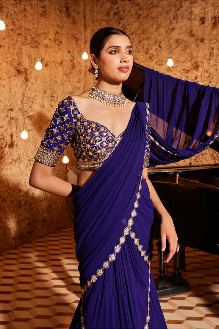 Indulge in elegance with this gorgeous purple drape sari in georgette, featuring exquisite embroidery detailing at the bottom and on the palla. The fully embroidered blouse adds a touch of sophistication to the ensemble. Padded for comfort, the blouse is designed with a side zip closure for a seamless fit. Elevate your style with this meticulously crafted outfit that exudes grace and timeless beauty. Traditional Draped Cutdana Blouse Piece, Festive Draped Georgette Blouse, Traditional Draped Blouse Piece With Cutdana, Silk Anarkali Saree With Draped Style, Evening Blouse In Georgette With Traditional Drape, Georgette Blouse With Traditional Drape For Evening, Unstitched Draped Anarkali Blouse, Traditional Drape Georgette Blouse For Reception, Anarkali Saree With Draped Unstitched Blouse