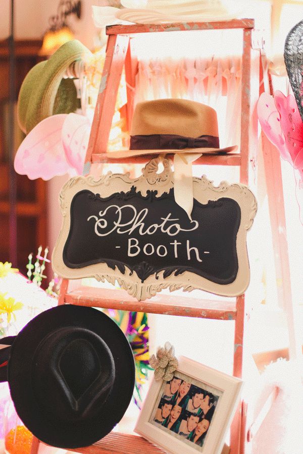 there is a sign that says photo booth next to a ladder with hats on it