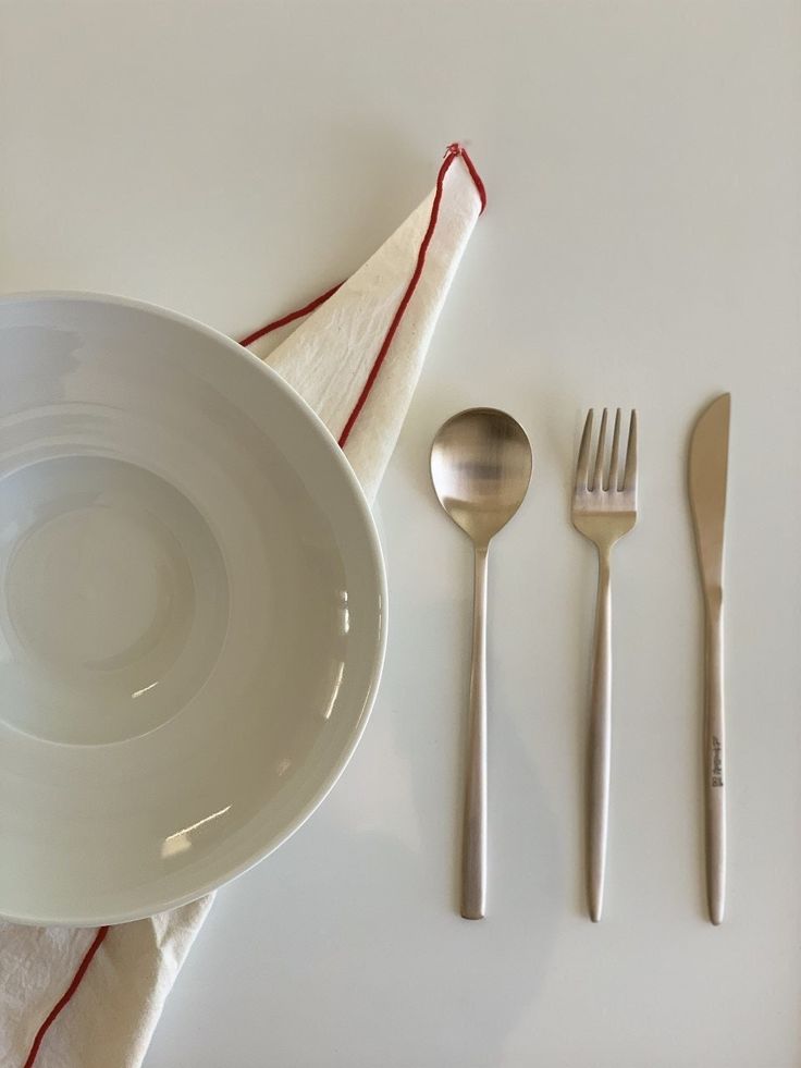 a white plate and silverware on top of a napkin next to utensils