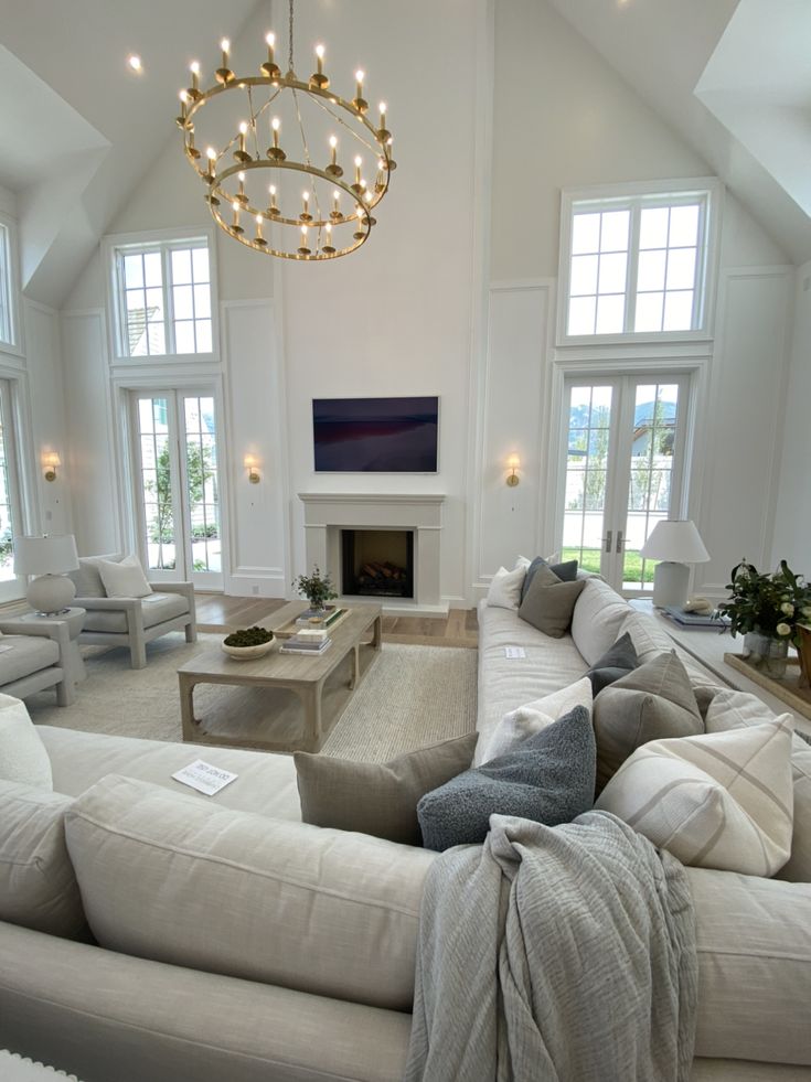 a living room filled with furniture and a chandelier hanging over the fire place