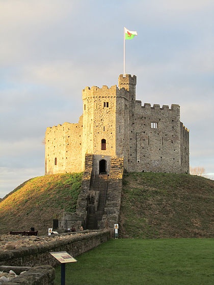 an old castle on top of a hill with a flag flying in the sky above it