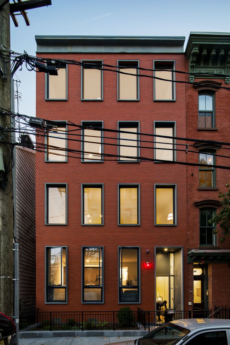 a red brick building with many windows on the front and side, along with power lines above it