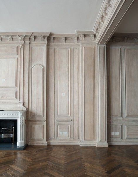 an empty room with wood flooring and white painted walls, along with a fireplace