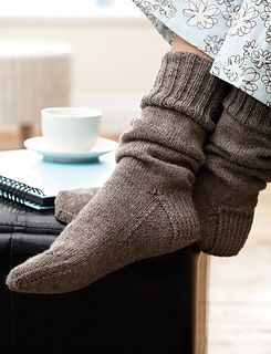 a person's feet with socks and a remote control on a table next to a suitcase