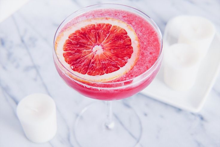 a grapefruit cocktail in a wine glass on a marble table