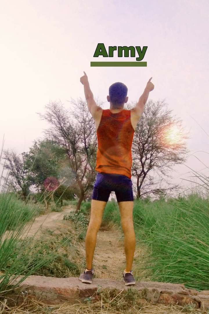 a man standing on top of a dirt road holding up an army sign above his head