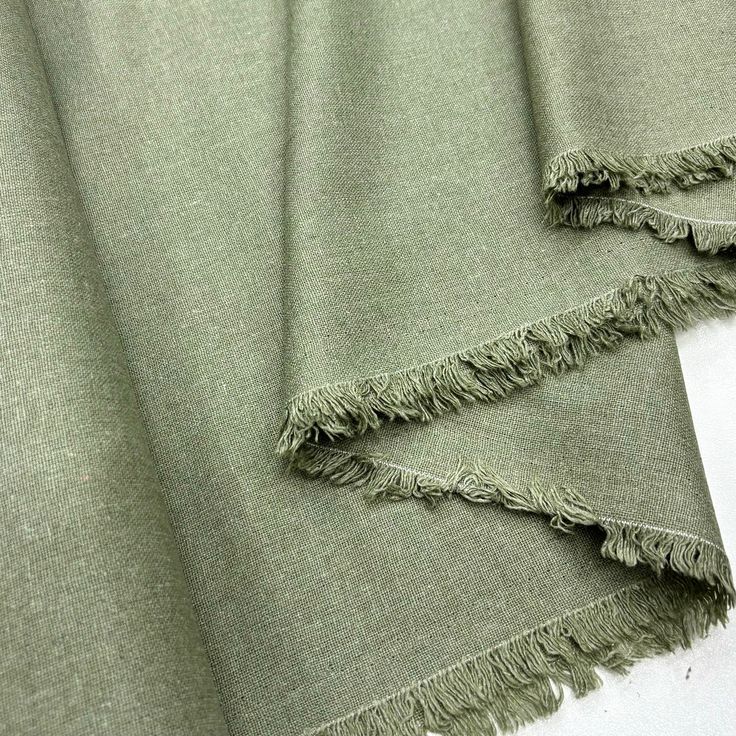 two pieces of green fabric with fringes on them