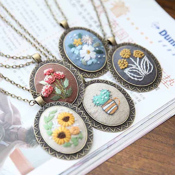 six different necklaces with flowers on them sitting on top of a table next to a magazine