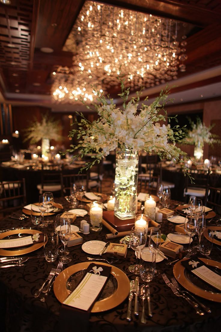 the centerpieces on this table are filled with white flowers and greenery as well as candles