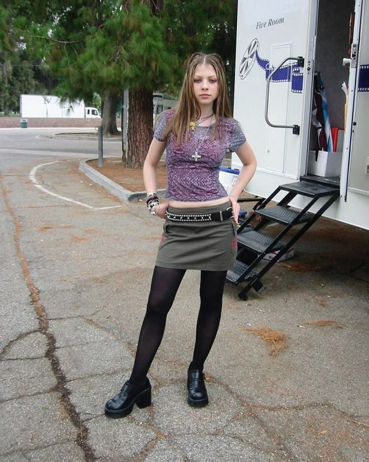 a young woman standing in front of a trailer with her hands on her hips and looking at the camera