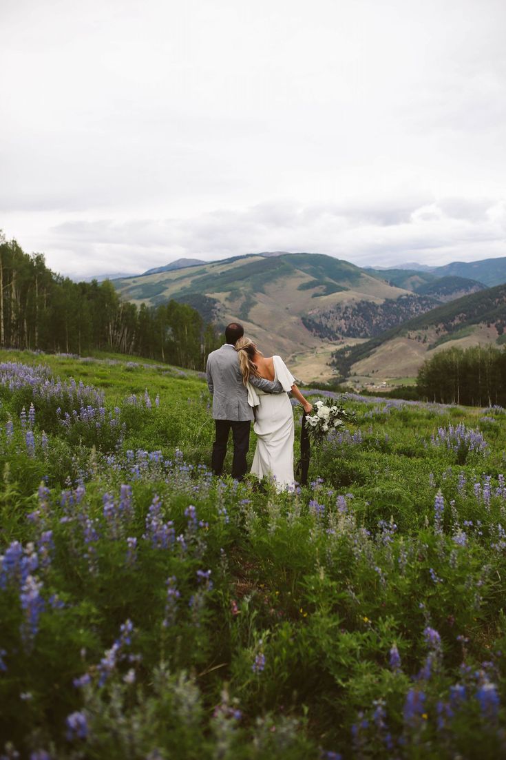 a bride and groom standing in the middle of a field full of wildflowers