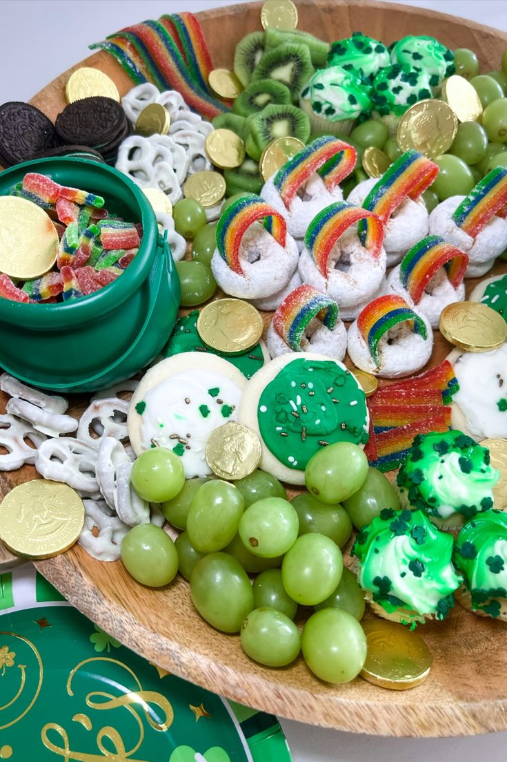 a wooden platter filled with lots of green and gold food on top of a table