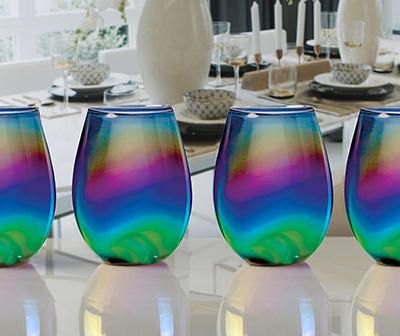 four colorful glasses sitting on top of a white table next to each other in front of a dining room table