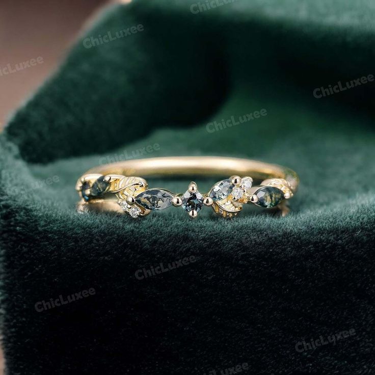 two gold rings sitting on top of a green velvet bag