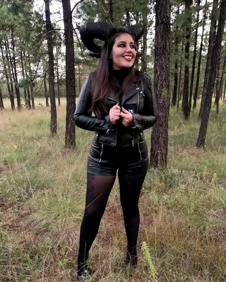 a woman standing in the middle of a forest with her hat on top of her head