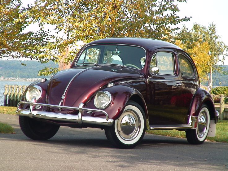 an old car is parked on the side of the road near some trees and water