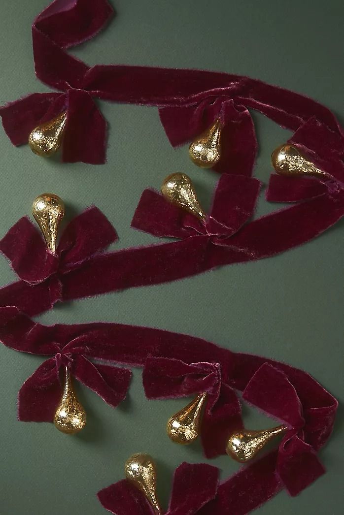 red velvet ribbon with gold metal bells attached to the end, on a green surface