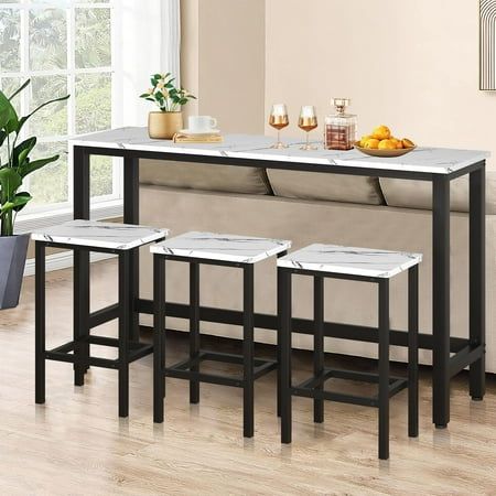 three stools and a table in front of a couch with potted plants on it