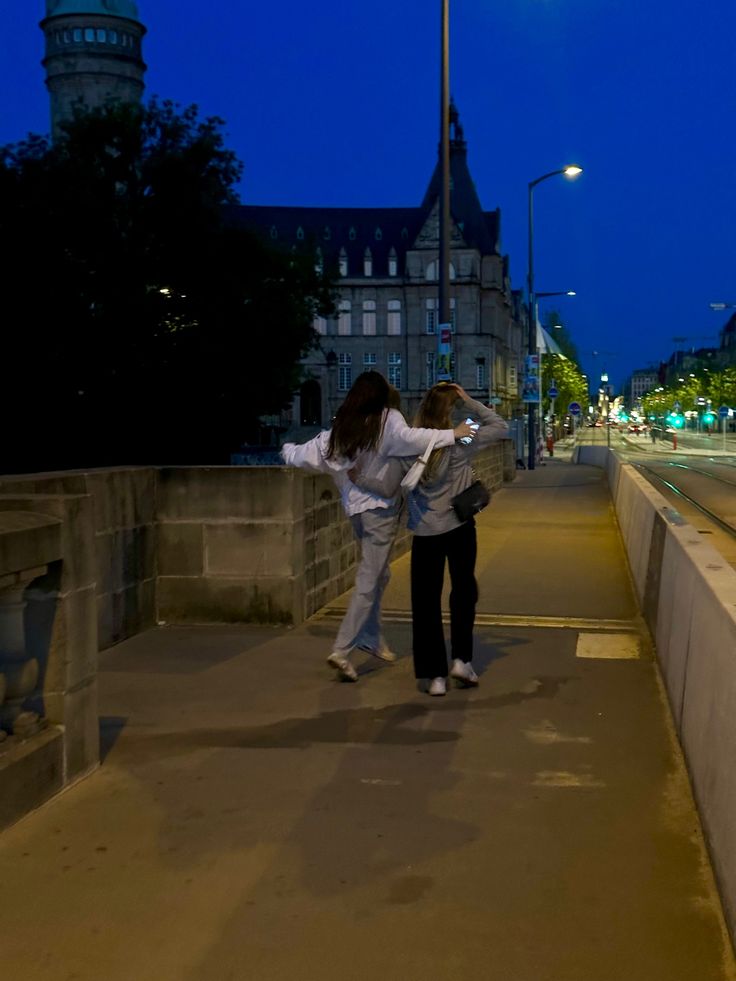 two people standing on a bridge at night